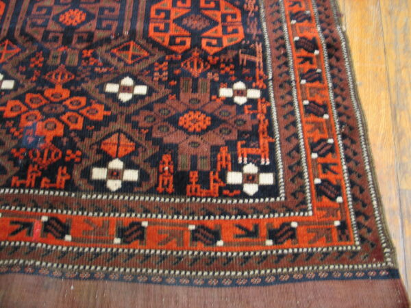 Geometric tribal rug in navy, rust, and orange with stylized figures, resting on light hardwood flooring.