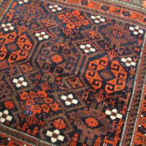 Detailed view of a rug with complex geometric patterns in navy, rust, brown, and cream.