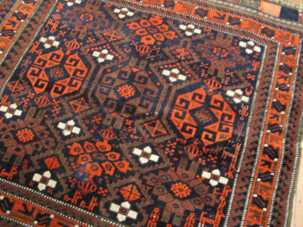 Detailed view of a rug with complex geometric patterns in navy, rust, brown, and cream.