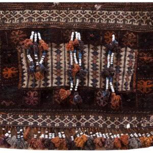 Dark brown textile featuring complex geometric patterns, contrasting textures, and ornamental tassels with white and blue beads.