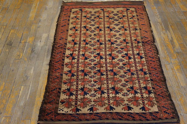 Low-pile rug in tan, rust, and navy geometric patterns displayed on wide plank wood floor.