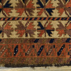 The rug features geometric bands in tan, terracotta, brown, and dark blue over wood flooring.