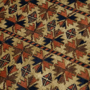 Geometric star and diagonal line patterns in rust, navy, and brown cover the low pile tan rug.