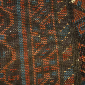 Dense, dark brown rug surface with contrasting geometric patterns in rust orange and blue.