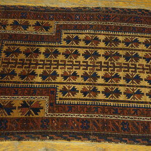 Geometric rug in brown, tan, and navy blue tribal patterns lays on a polished wood floor.