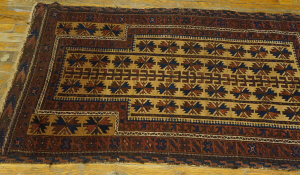 Geometric rug in brown, tan, and navy blue tribal patterns lays on a polished wood floor.