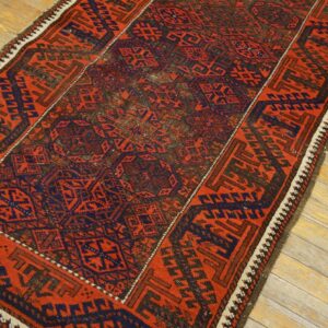 Red and navy geometric runner rug with tribal motifs resting on light, weathered wood flooring.