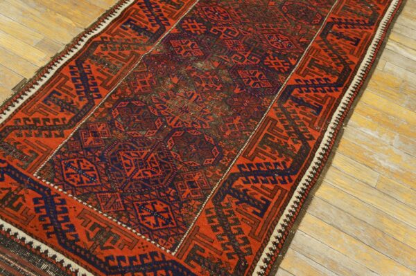 Red and navy geometric runner rug with tribal motifs resting on light, weathered wood flooring.
