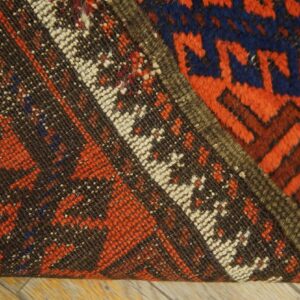 A rug folded back reveals the dark brown, low-weave backing contrasting with the thick red and blue pile.