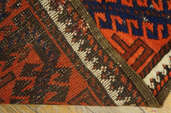 A rug folded back reveals the dark brown, low-weave backing contrasting with the thick red and blue pile.