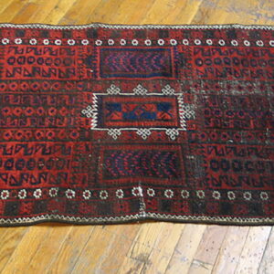 Red and dark blue geometric runner rug with ivory accents lying on a glossy hardwood floor.