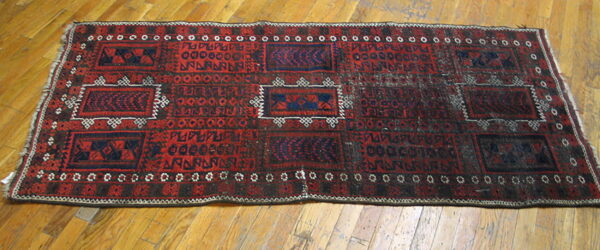 Red and dark blue geometric runner rug with ivory accents lying on a glossy hardwood floor.