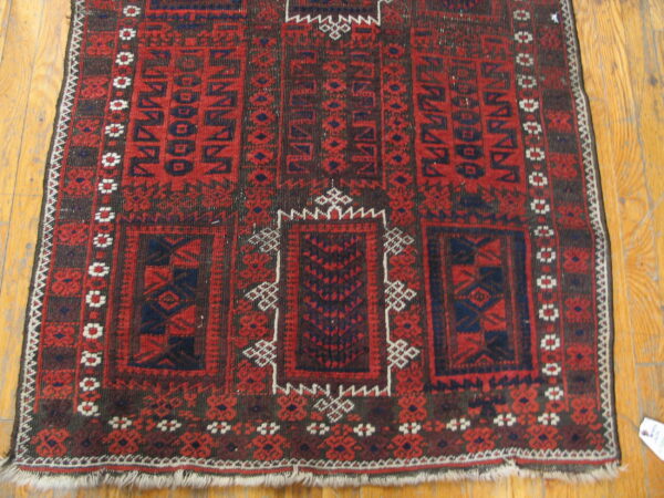 Rustic red and navy geometric rug with white accents rests on light wooden plank flooring.