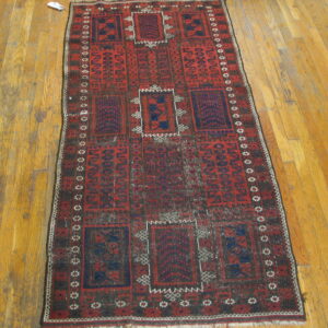 Geometric red and dark blue runner rug with repeating central medallions on plank hardwood flooring.