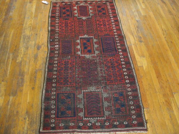 Geometric red and dark blue runner rug with repeating central medallions on plank hardwood flooring.