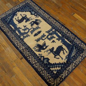 Rectangular blue and cream rug featuring animal and tree motifs within a geometric border on wood flooring.
