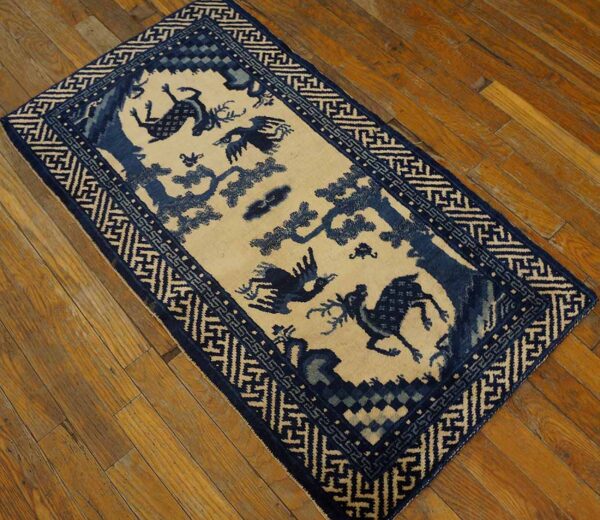 Rectangular blue and cream rug featuring animal and tree motifs within a geometric border on wood flooring.