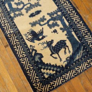 Blue and cream runner rug with a deer and bird pictorial pattern sits on light brown plank flooring.