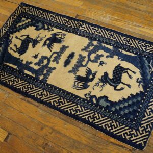 Blue and beige rug featuring stylized birds and deer within a geometric border, resting on wood flooring.
