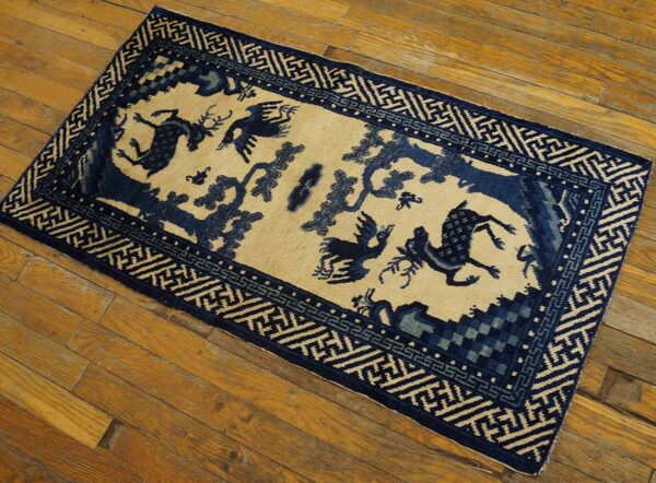 Blue and beige rug featuring stylized birds and deer within a geometric border, resting on wood flooring.