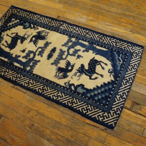 Rectangular blue and beige low-pile rug featuring animal motifs and a geometric border on distressed wood planks.
