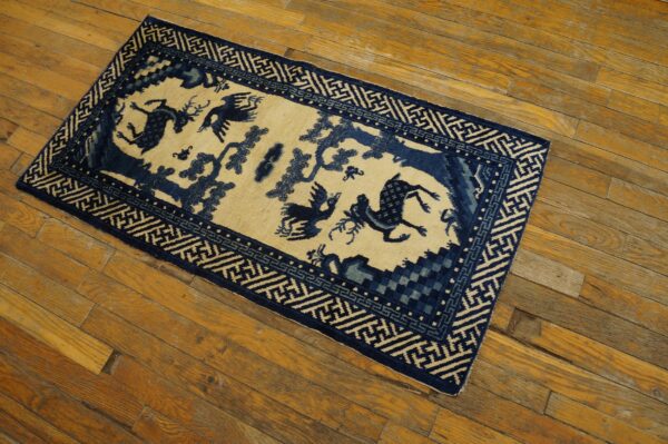 Rectangular blue and beige low-pile rug featuring animal motifs and a geometric border on distressed wood planks.