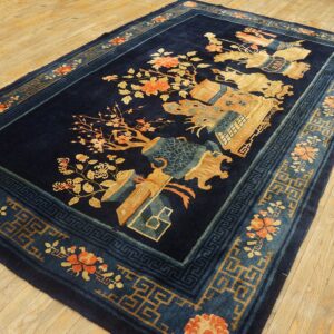 Navy blue rug with gold, orange, and teal floral and geometric patterns on wood flooring.