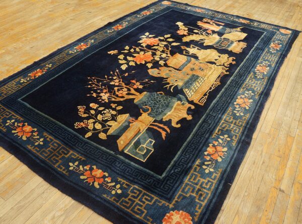 Navy blue rug with gold, orange, and teal floral and geometric patterns on wood flooring.