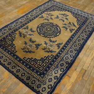 A low-pile rug in gold and navy blue with geometric and floral patterns on worn wood planks.