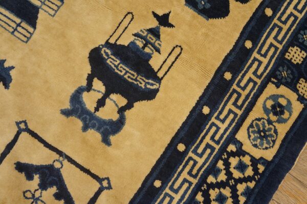 Golden yellow and navy blue plush rug displaying an urn motif and geometric meander border design.