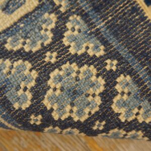 Navy, light blue, and cream geometric rug detail showing tight texture over wood flooring.