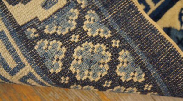 Navy, light blue, and cream geometric rug detail showing tight texture over wood flooring.