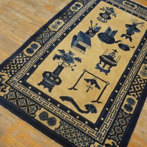 Tan and blue rug featuring stylized vases and objects, bordered by geometric patterns on light wood flooring.