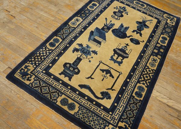 Tan and blue rug featuring stylized vases and objects, bordered by geometric patterns on light wood flooring.