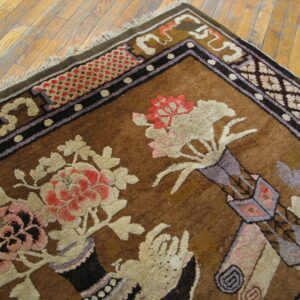 Brown, high-pile rug with stylized red and cream floral patterns and a complex border on wood plank flooring.
