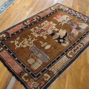 Brown rug with beige and pink floral still-life patterns and dark borders on hardwood floor.