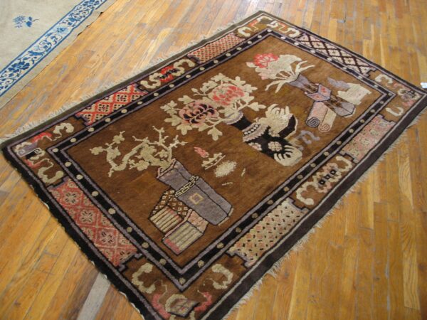 Brown rug with beige and pink floral still-life patterns and dark borders on hardwood floor.