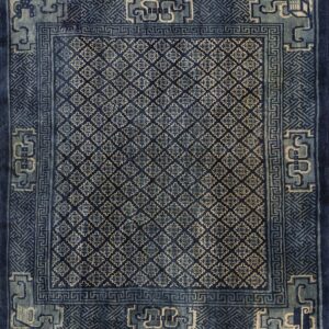 Dark blue rug displaying small repeating floral geometric motifs bordered by complex light blue designs.
