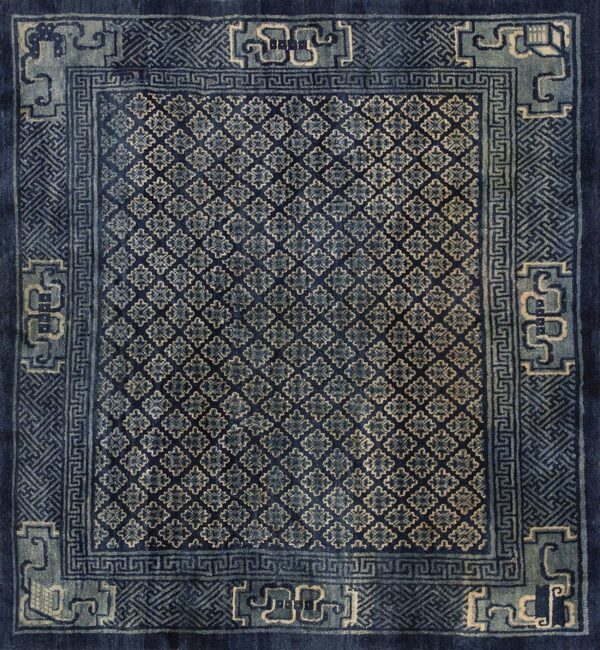 Dark blue rug displaying small repeating floral geometric motifs bordered by complex light blue designs.