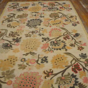 Ivory rug with sprawling floral vines in muted pink, gold, and charcoal on rustic wood floors.