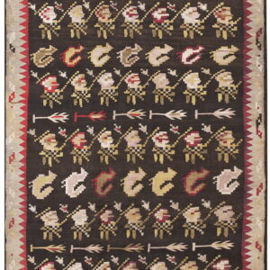 Geometric folk rug with a dark field patterned by rows of figures and arrows in cream, red, and yellow.