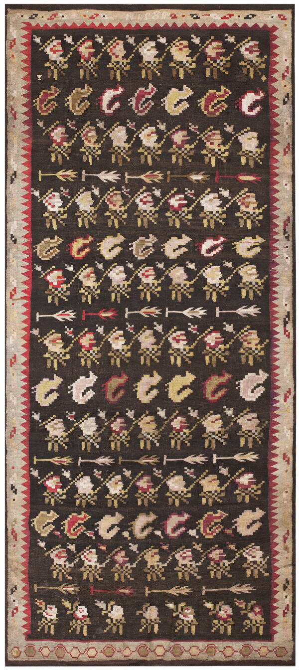 Geometric folk rug with a dark field patterned by rows of figures and arrows in cream, red, and yellow.