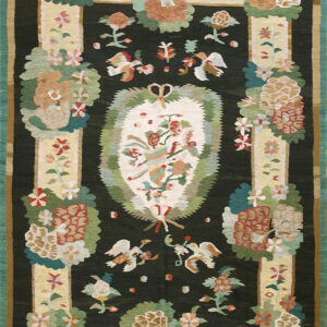 Black rug with a large oval floral medallion surrounded by stylized flowers and flying bird motifs.