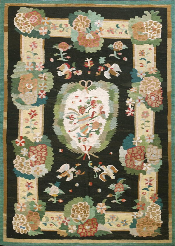 Black rug with a large oval floral medallion surrounded by stylized flowers and flying bird motifs.