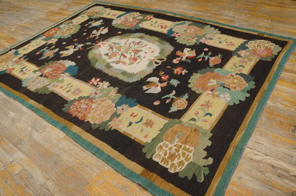 Square dark brown rug with a colorful floral and bird medallion pattern resting on light wood planks.