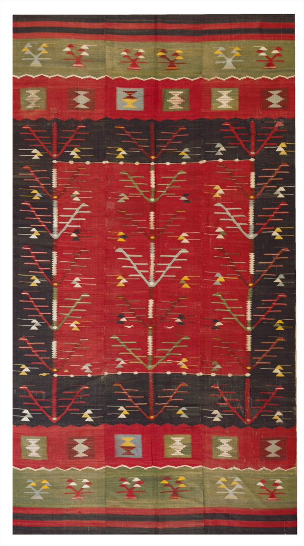 Flatwoven rug in red, black, and olive green with repeating geometric tree and medallion motifs.