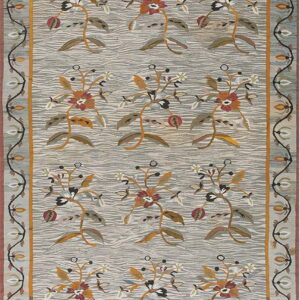 Light gray rug with wavy texture and rows of stylized floral motifs in gold, rust, and olive, framed by a complex scrolled border.