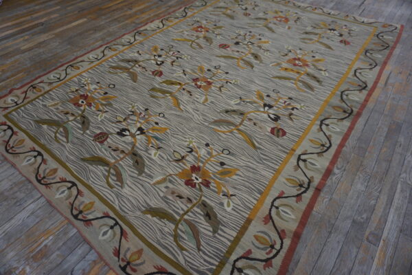 Large gray and cream rug featuring gold and maroon florals and a vine border on distressed gray planks.