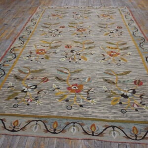 Low-pile rug with gray wavy lines and colorful, repeating floral designs resting on distressed wood floors.