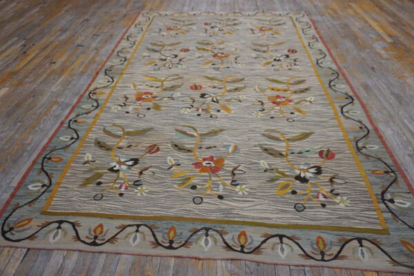 Low-pile rug with gray wavy lines and colorful, repeating floral designs resting on distressed wood floors.